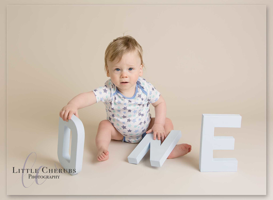 first birthday baby holding ONE letters cake smash photography cambridge little cherubs
